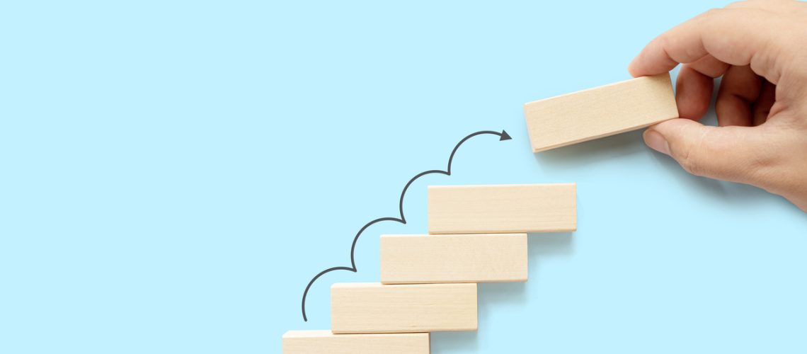 Ladder career path for business growth success process concept. Hand arranging wood block stacking as step stair with arrow up
