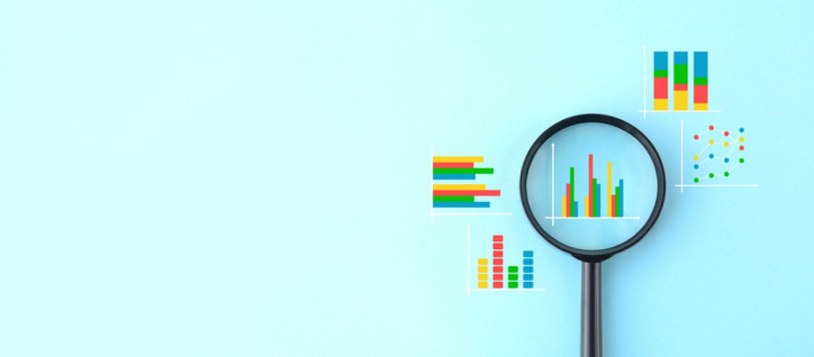 Magnifying glass and various business graphs on light blue background