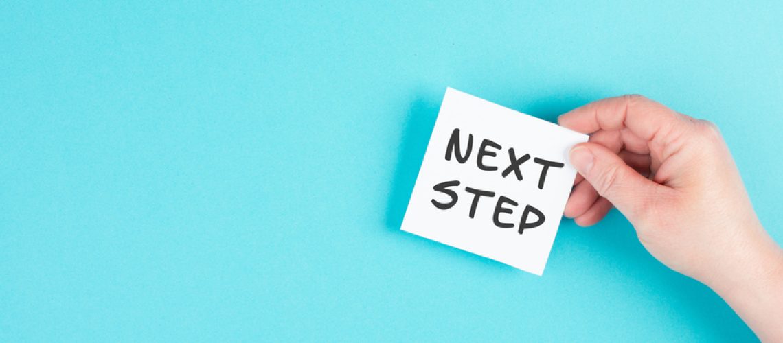 The phrase next step is standing on a paper, having new goals and strategies, making plans for future