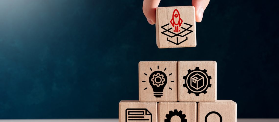 Product development, launching, analysis and market validation. MVP, minimum viable product concept for lean startup. Product development, launching, analysis and market validation. MVP, minimum viable product concept for lean startup. Hand puts wooden cubes with new product launch icons.