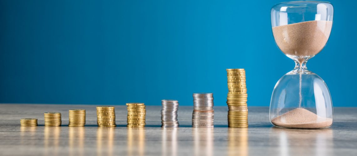 Coins and hourglass on wooden table