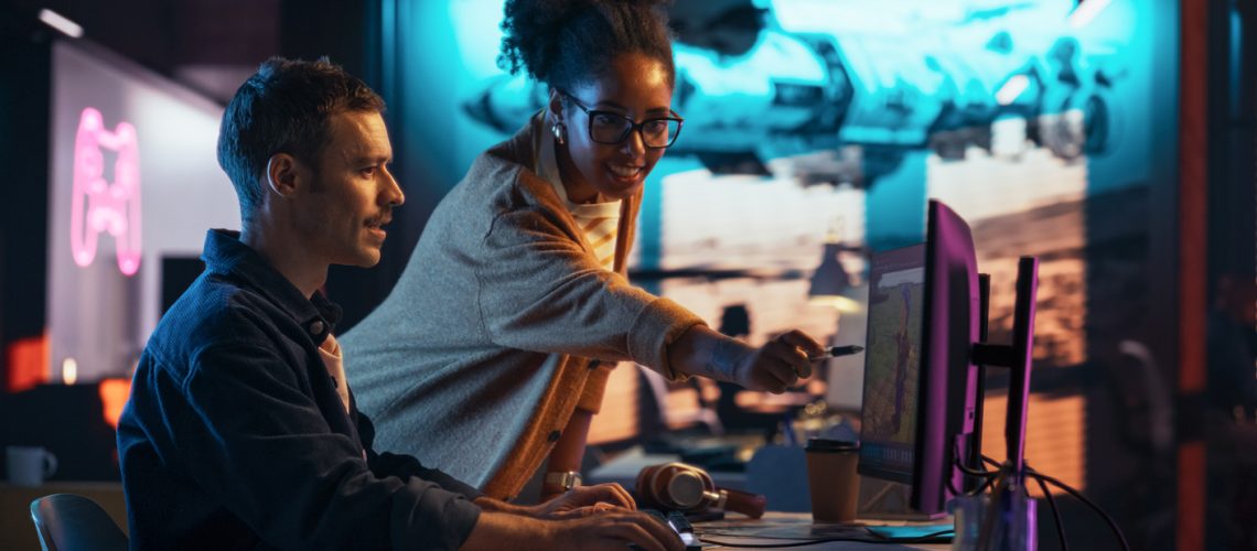 Portrait of Black Creative Director and Male Developer Talking About Work in Creative Agency. Two Stylish Diverse Employees Discussing Character Design on Computer in Game Development Company