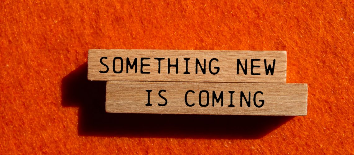 Something new is coming message written on wooden blocks on orange felt background. Conceptual something new is coming symbol. Copy space.