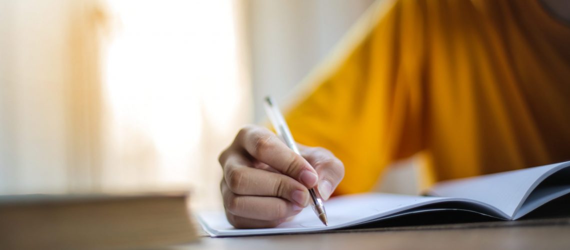 pexels-andrea-piacquadio-3807741 writing on a notebook